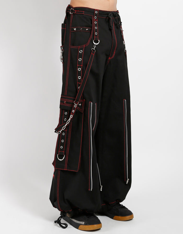 Black classic fit Tripp pants with red stitching, zipper details, removable straps on the back, drawstrings near the feet to tighten the fit, and red skulls printed on the back of each leg.