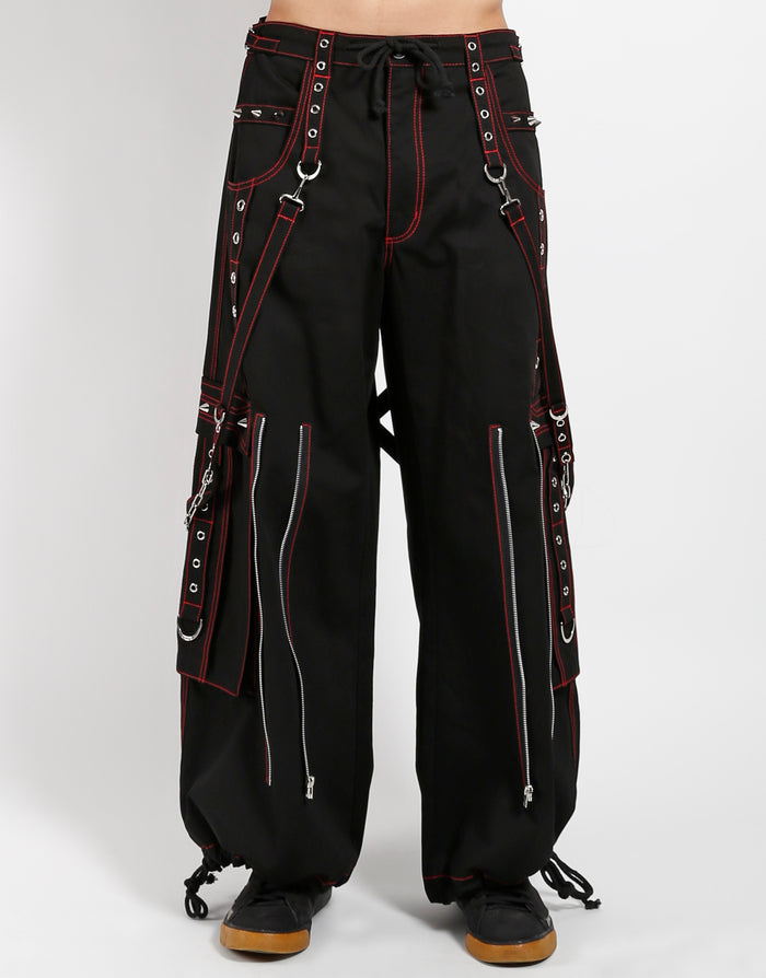 Black classic fit Tripp pants with red stitching, zipper details, removable straps on the back, drawstrings near the feet to tighten the fit, and red skulls printed on the back of each leg.