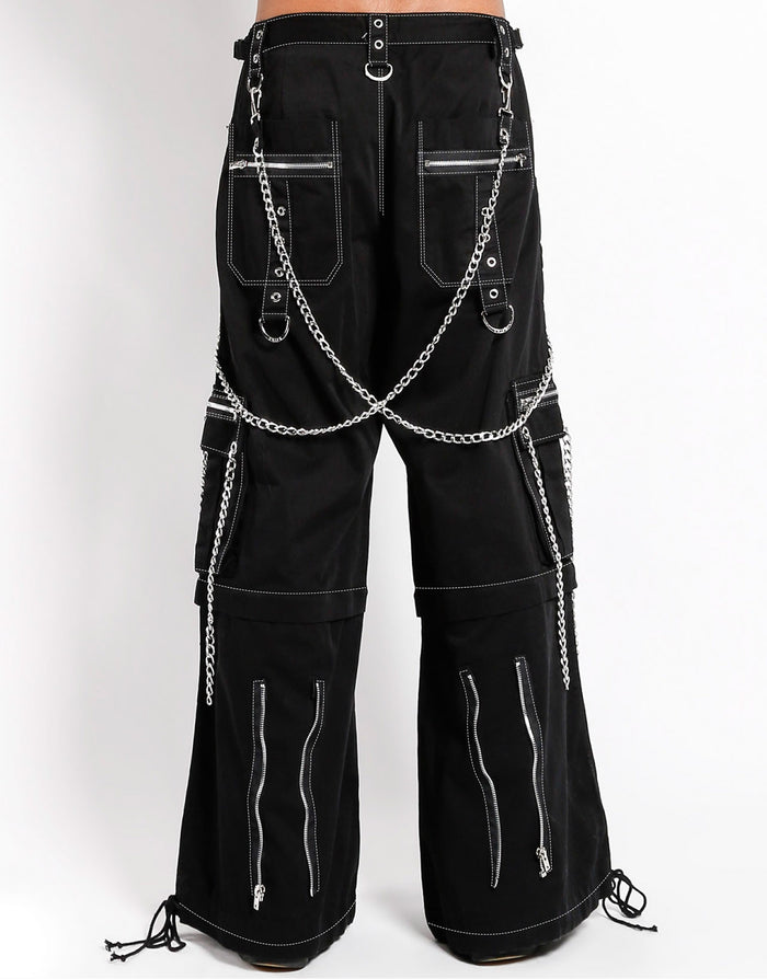 back view of Black baggy Tripp pants with white stitching. Pants have front rivet details, side pocket hanging chain details, removable attached chains, back zipper details and more. Pant legs can also zip off into shorts.