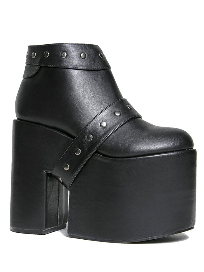 side view of black vegan leather super tall 6" heel, 4" platform sleep design boot. Boot has a rivet studded strap that wraps around and is removable or attachable with Velcro. Boot has black EVA platform.