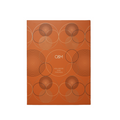 A rectangular orange box with a geometric pattern of overlapping circles in black and light beige lines, featuring the text 'O&M VOLUMISE AND THICKEN' in the center, shown on a plain white background.